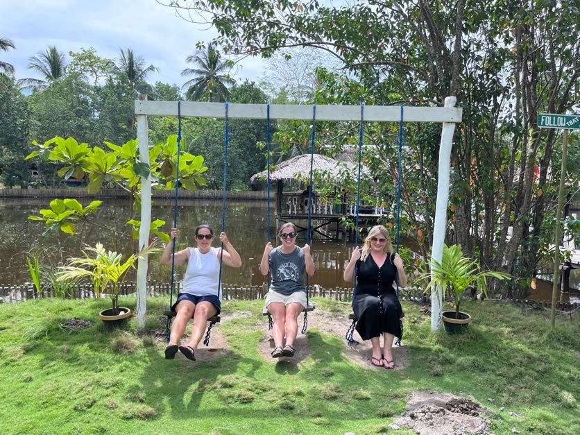 Rihana Ravindran, Taylor Higgins and Lauren Higgins enjoying the swings at Buluang Fishpond Restaurant, Coron, Philippines